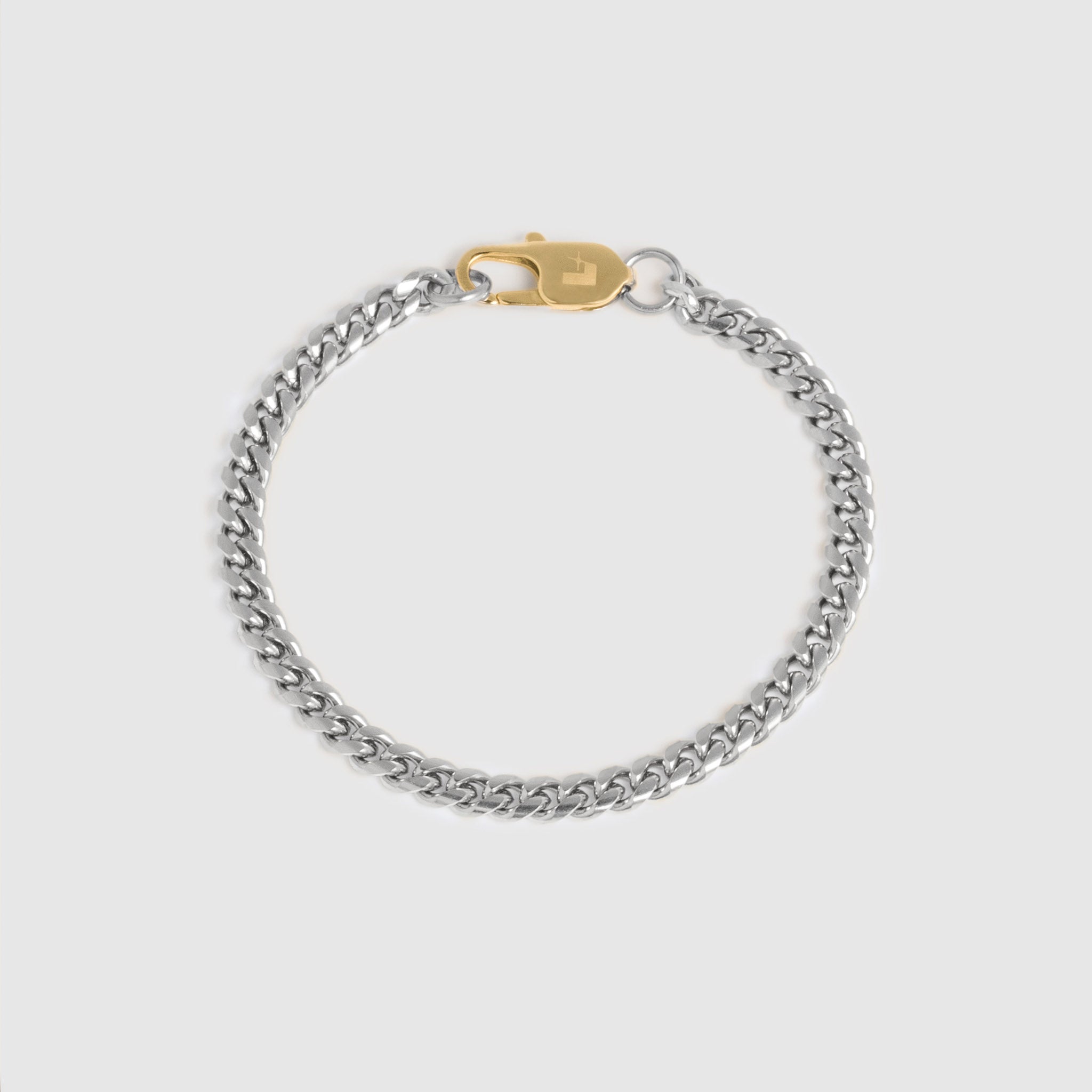 A silver-toned curb chain bracelet with a gold-toned lobster clasp, displayed on a light gray background.