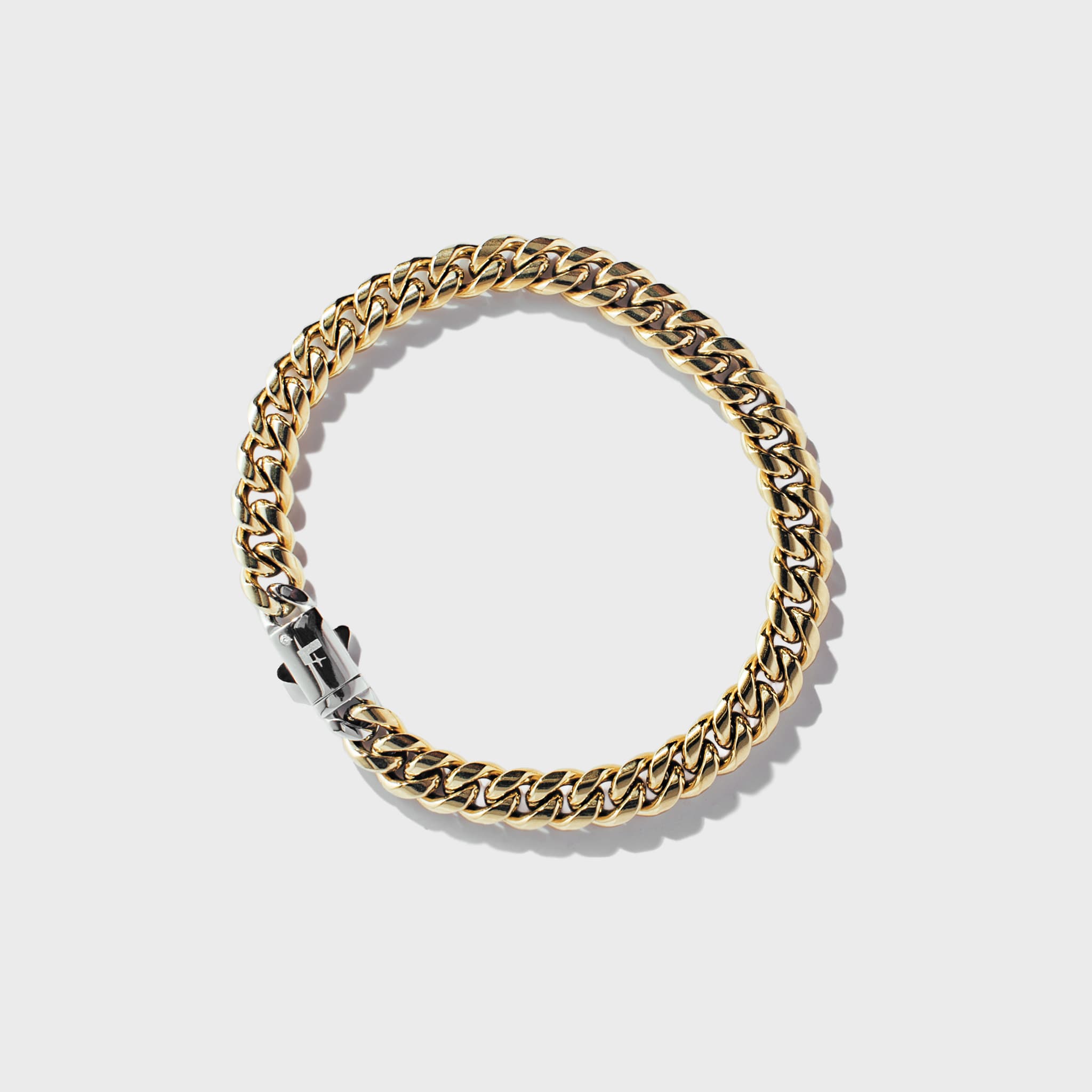 Gold thick chain bracelet with silver clasp on white background