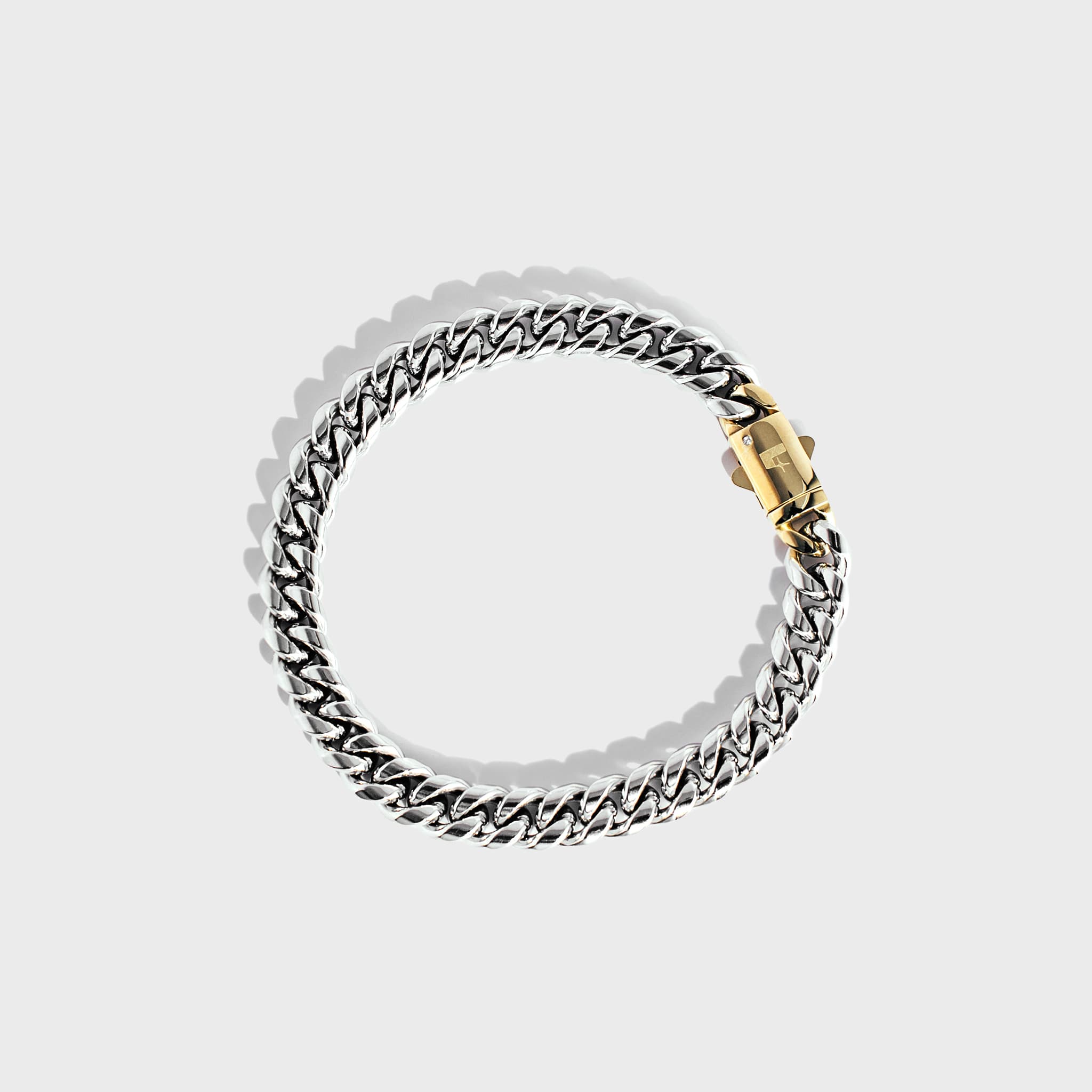 Silver thick chain bracelet with gold clasp on white background