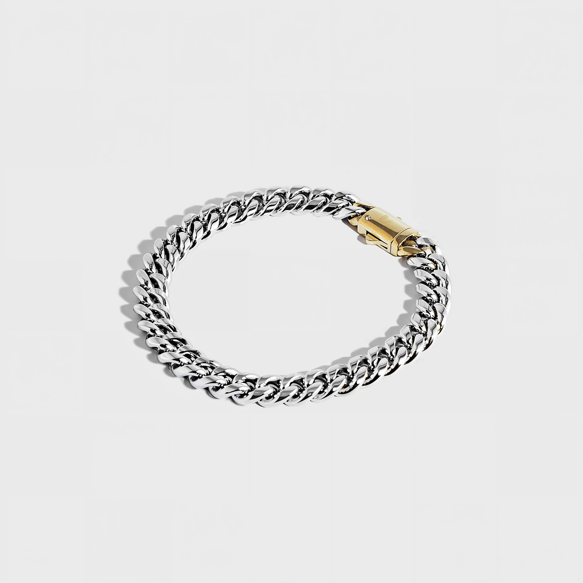 Silver thick chain bracelet with gold clasp on white background