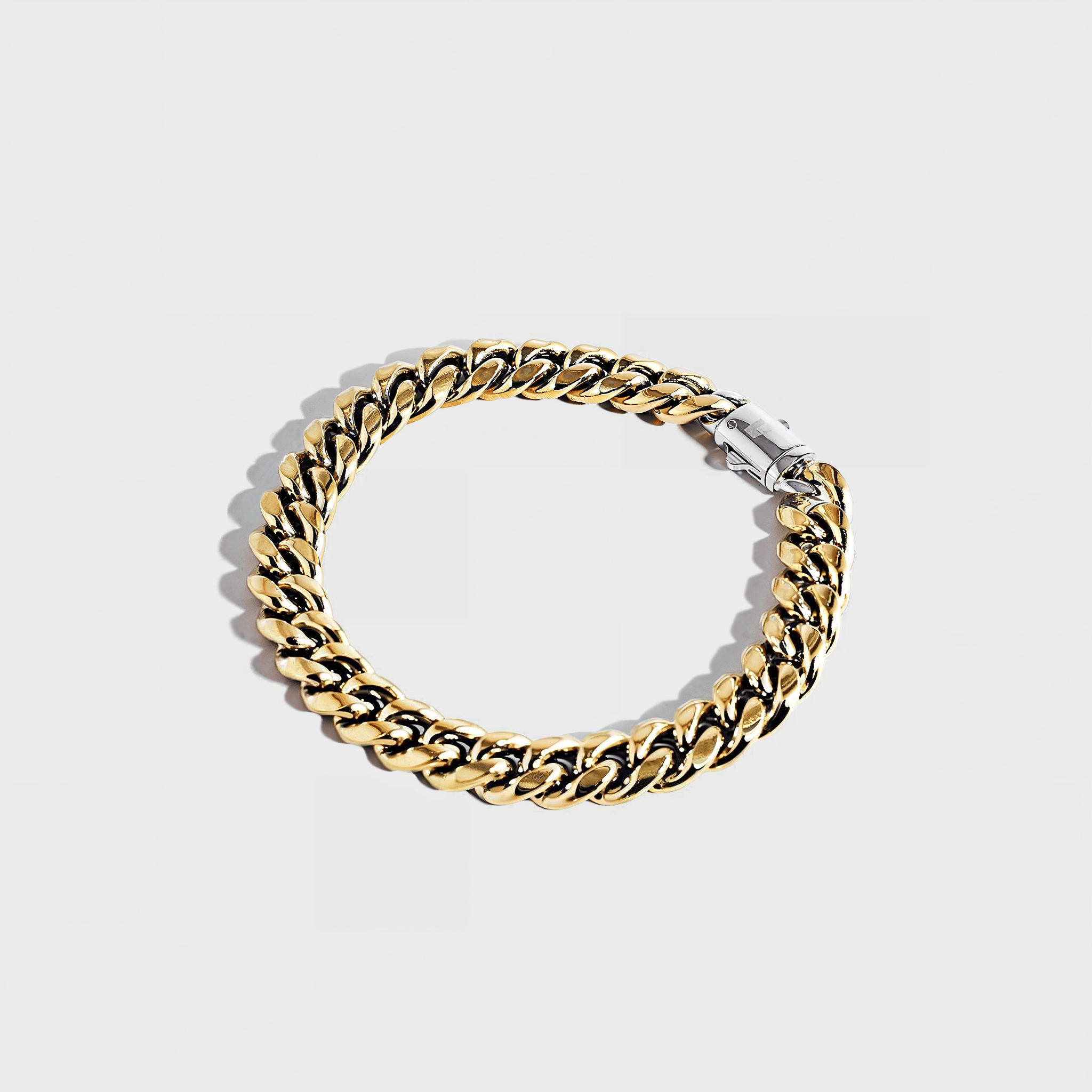 Gold thick chain bracelet with silver clasp on white background