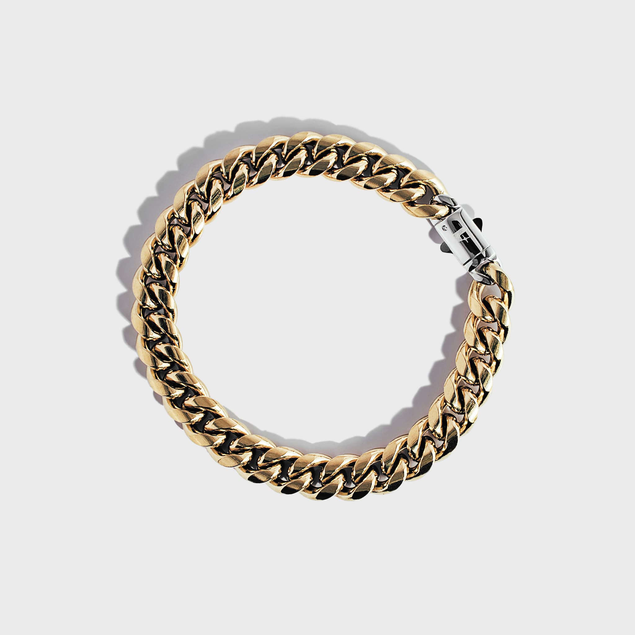 Gold thick chain bracelet with silver clasp on white background