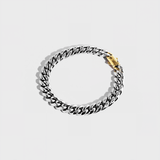 Silver thick chain bracelet with gold clasp on white background
