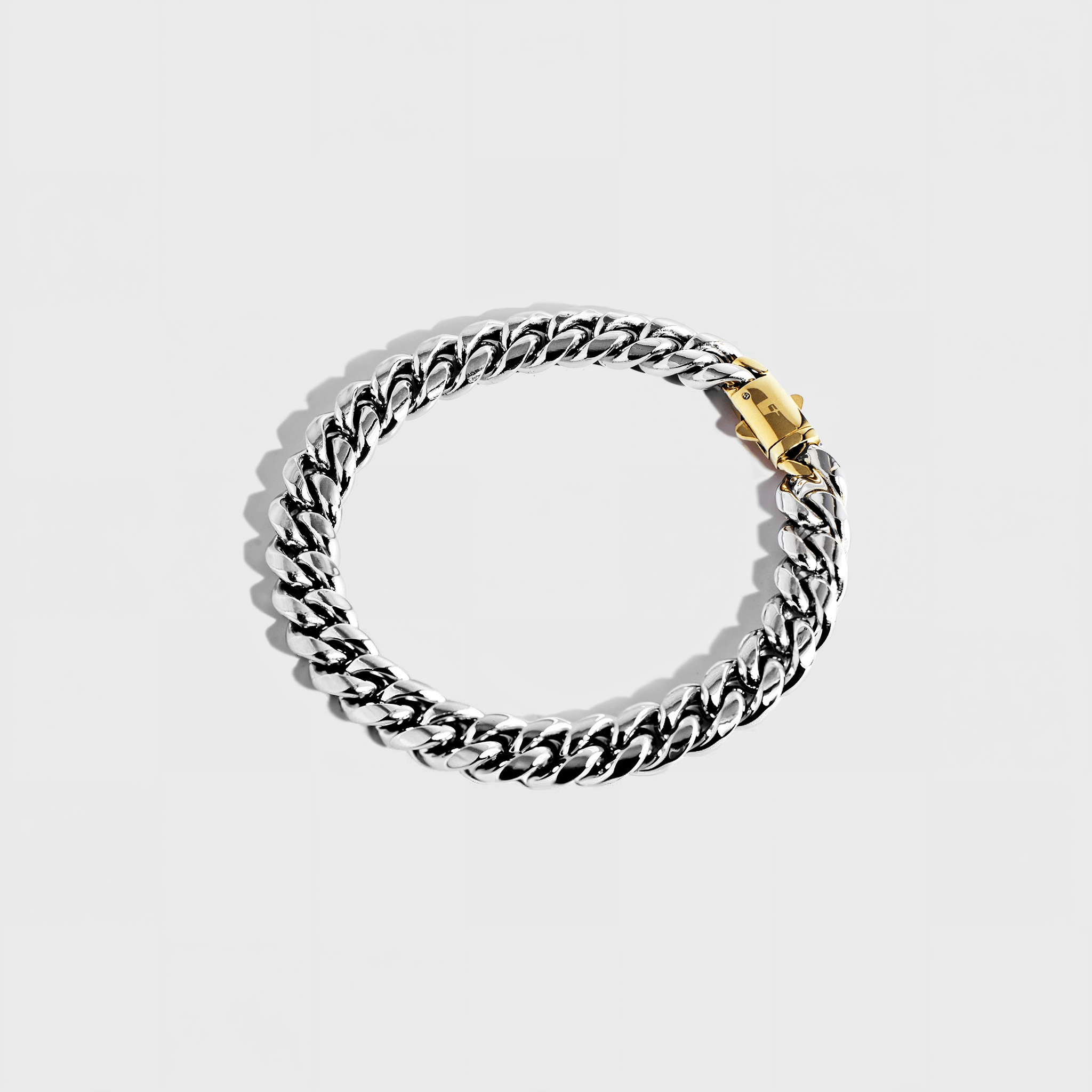 Silver thick chain bracelet with gold clasp on white background
