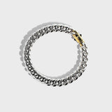 Silver thick chain bracelet with gold clasp on white background
