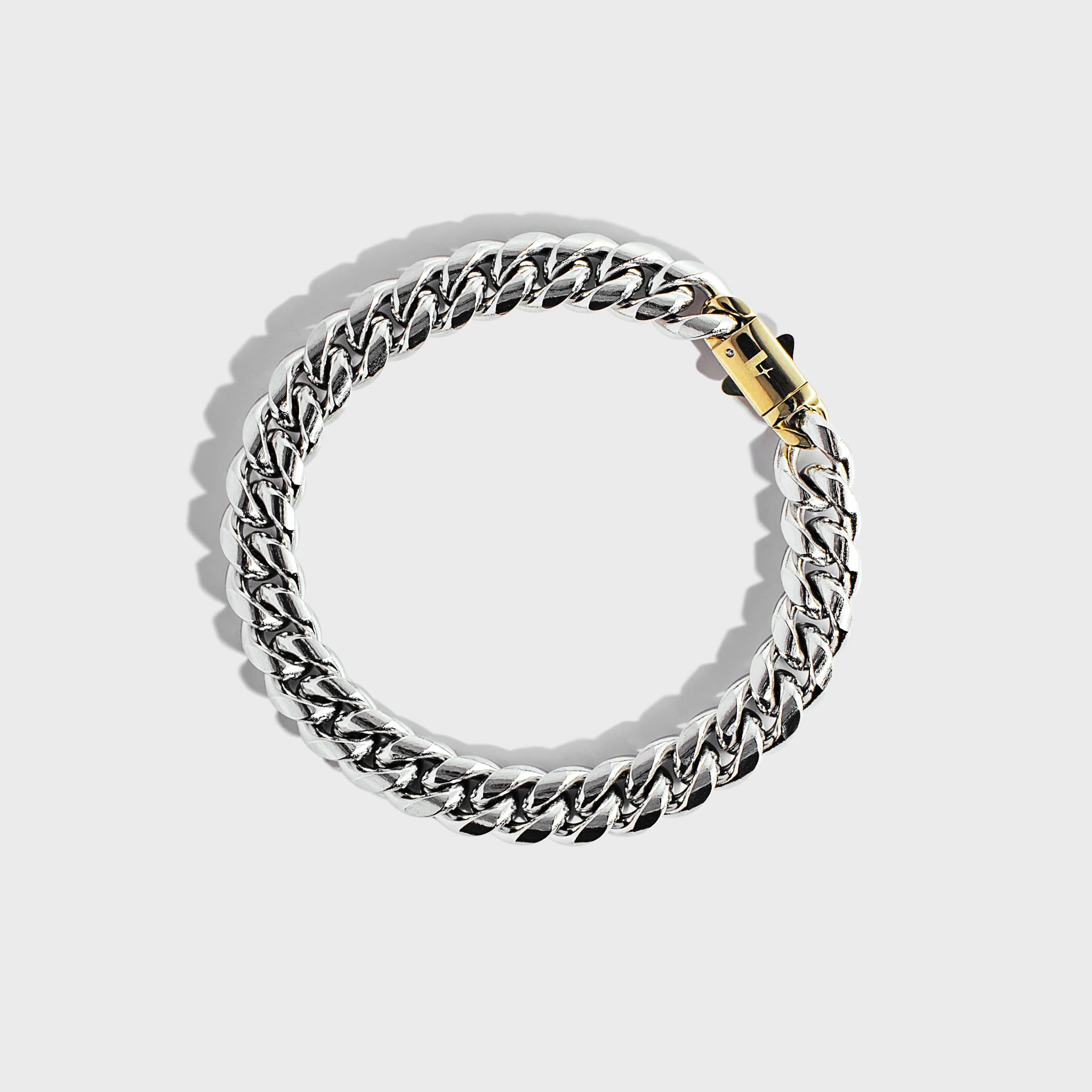 Silver thick chain bracelet with gold clasp on white background
