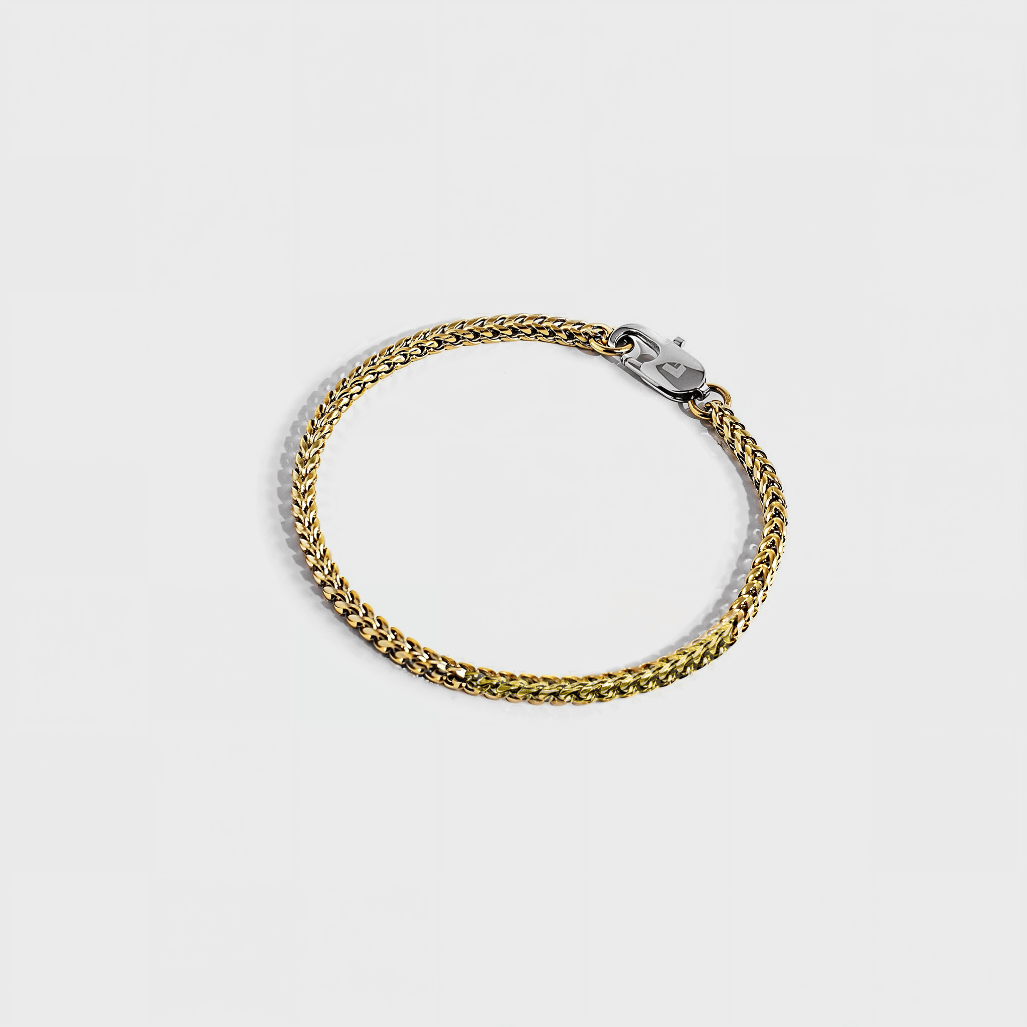 Gold chain bracelet with silver oval clasp with white background