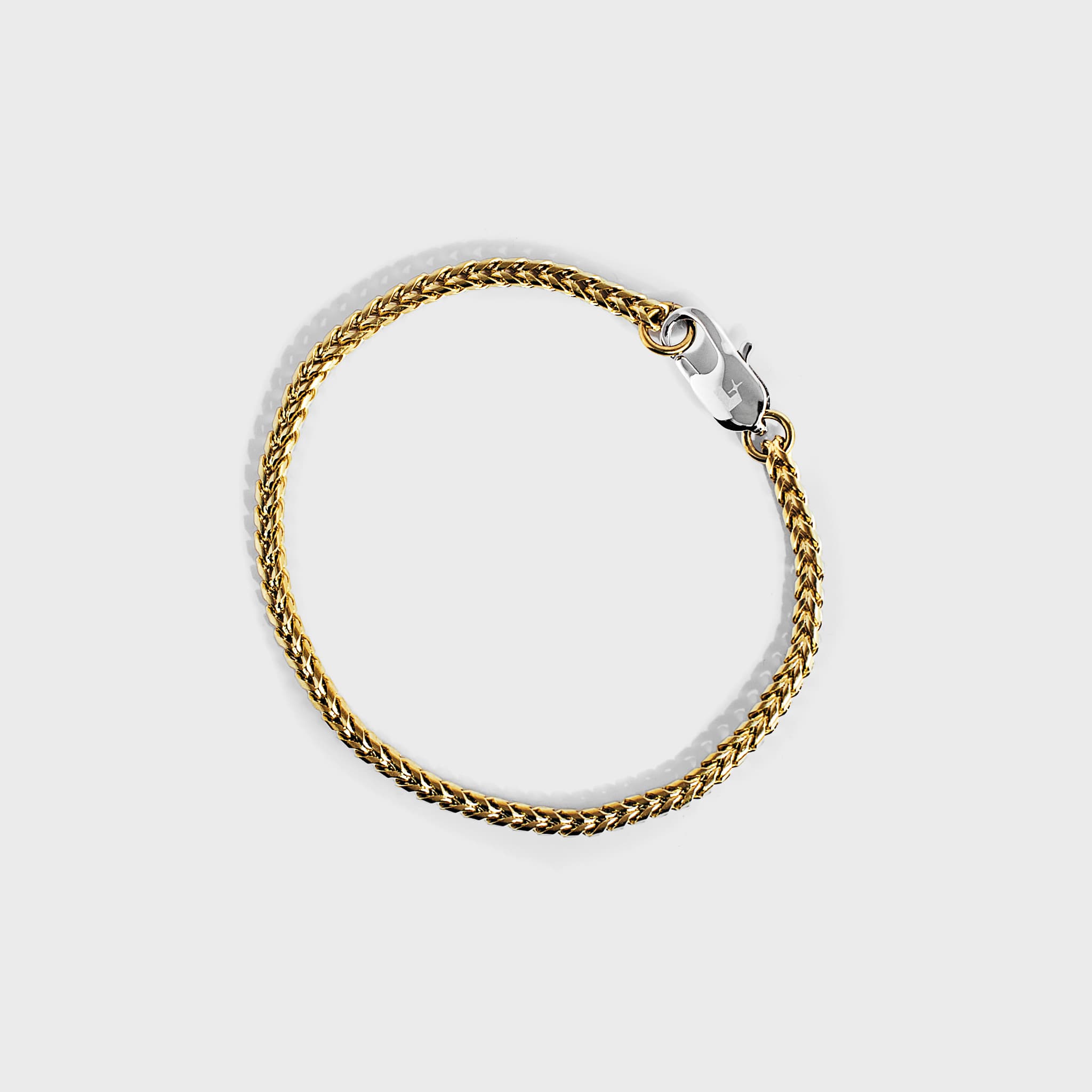 Gold chain bracelet with silver oval clasp with white background 