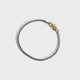 Silver chain bracelet with gold oval clasp on white background