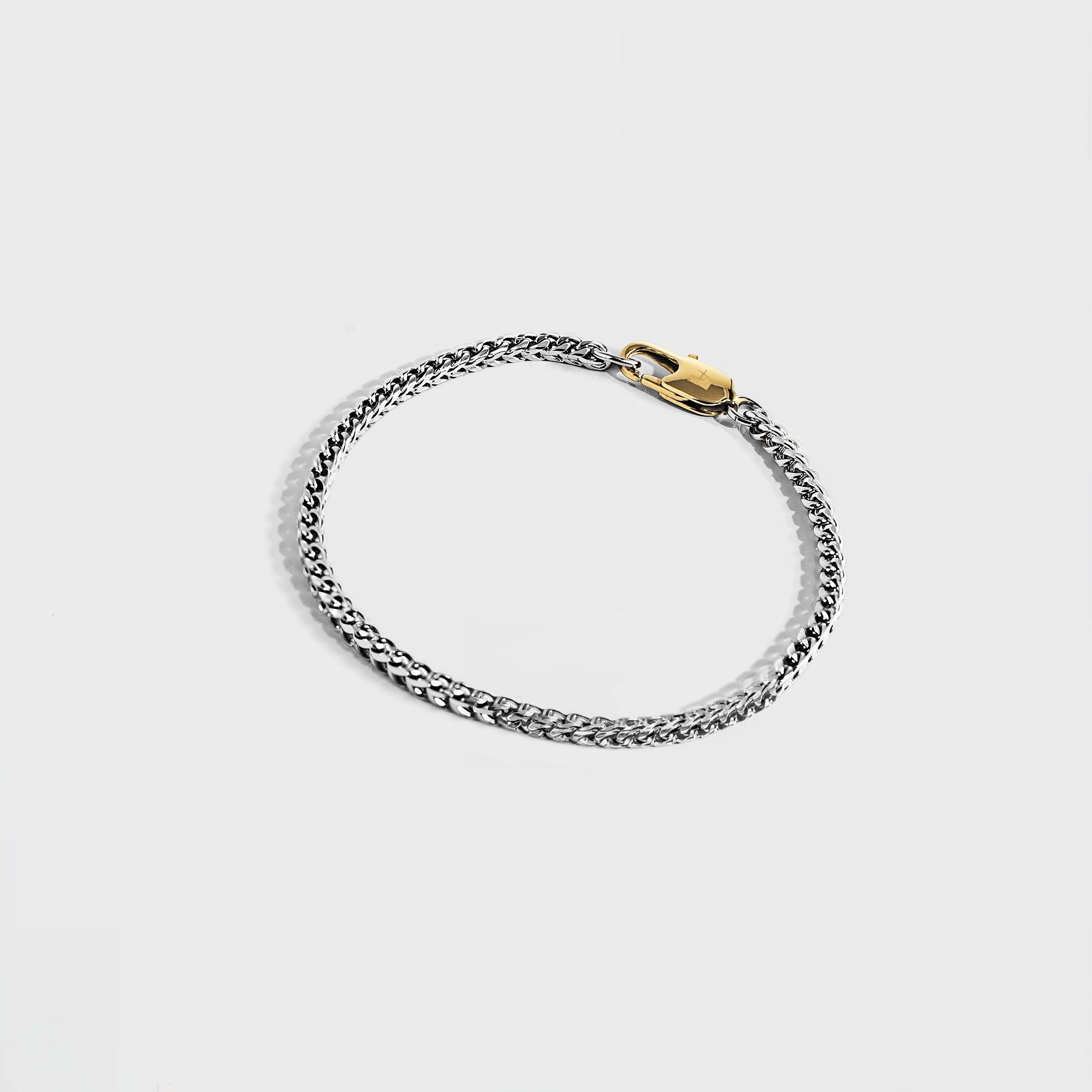 Silver chain bracelet with gold oval clasp on white background