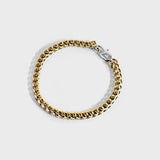 Gold chain bracelet with silver oval clasp on white background