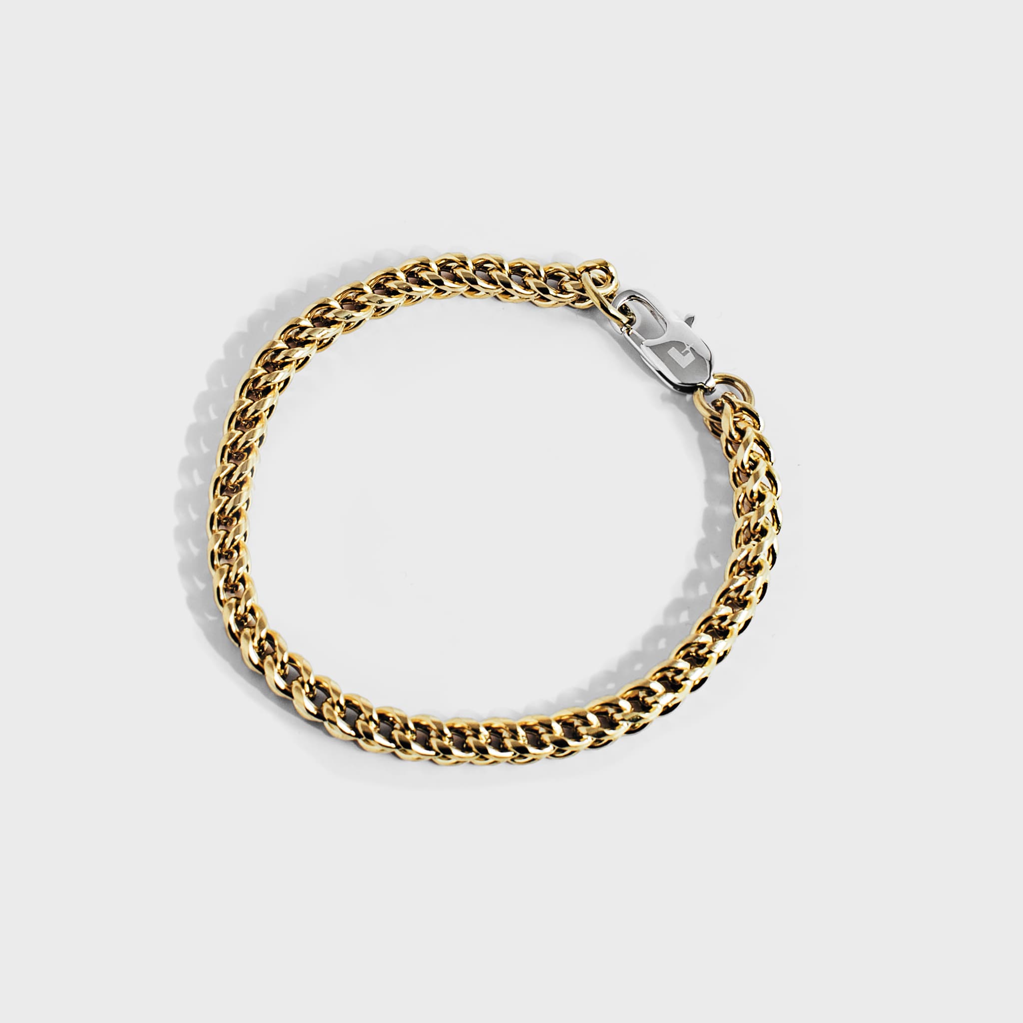 Gold chain bracelet with silver oval clasp on white background
