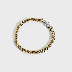 Gold chain bracelet with silver oval clasp on white background