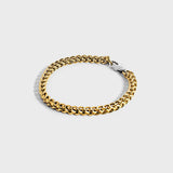 Gold chain bracelet with silver oval clasp on white background