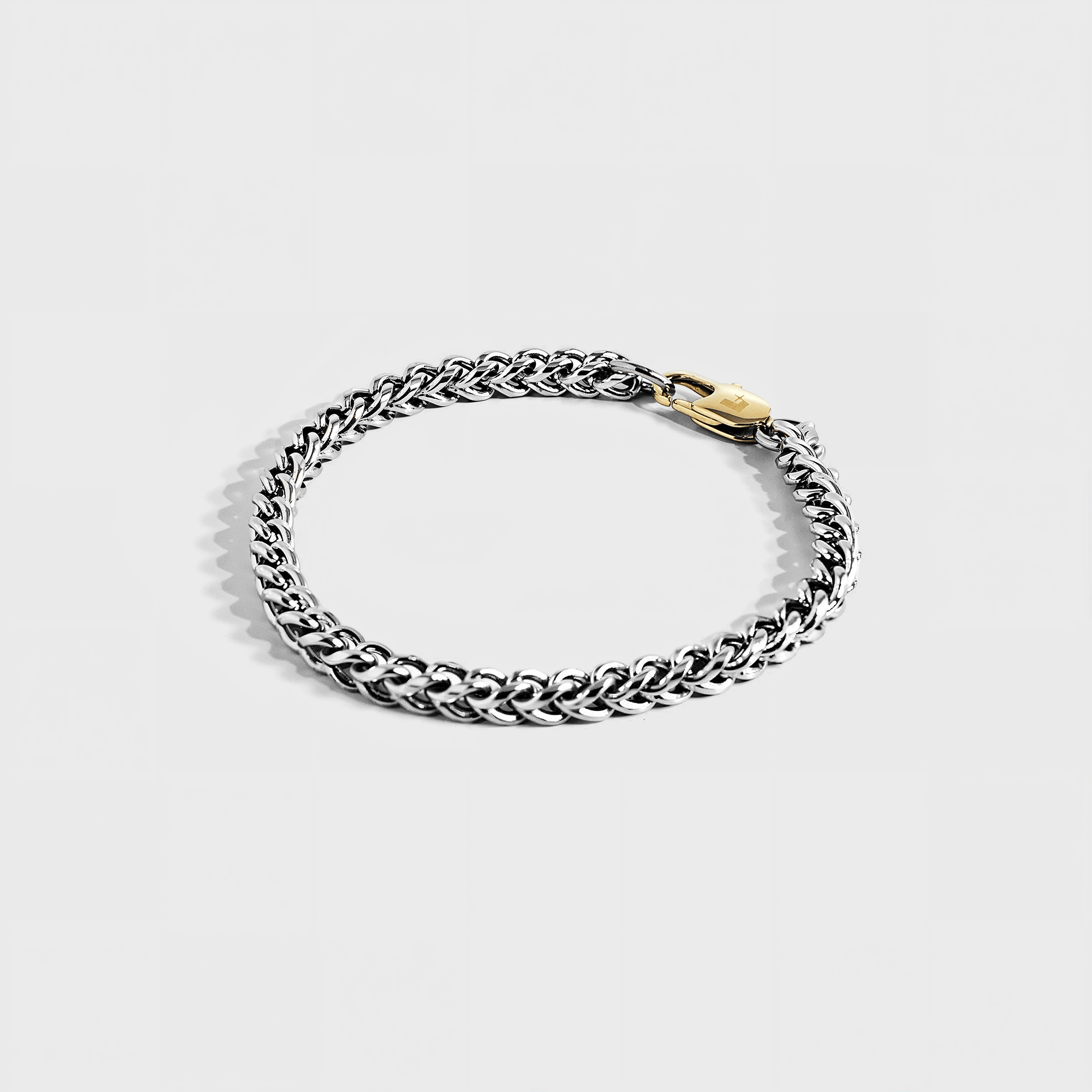 Silver chain bracelet with gold oval clasp on white background