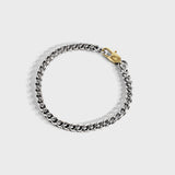 Silver chain bracelet with gold oval clasp on white background
