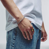 A close-up of a person wearing a silver hex chain link bracelet on their wrist, paired with a white t-shirt and blue jeans.