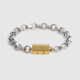 A two-tone chain bracelet featuring a silver-toned hex link chain and a central gold-toned cube clasp, displayed on a light gray background.