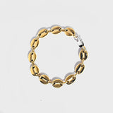 Gold mariner chain bracelet with silver oval clasp on white background