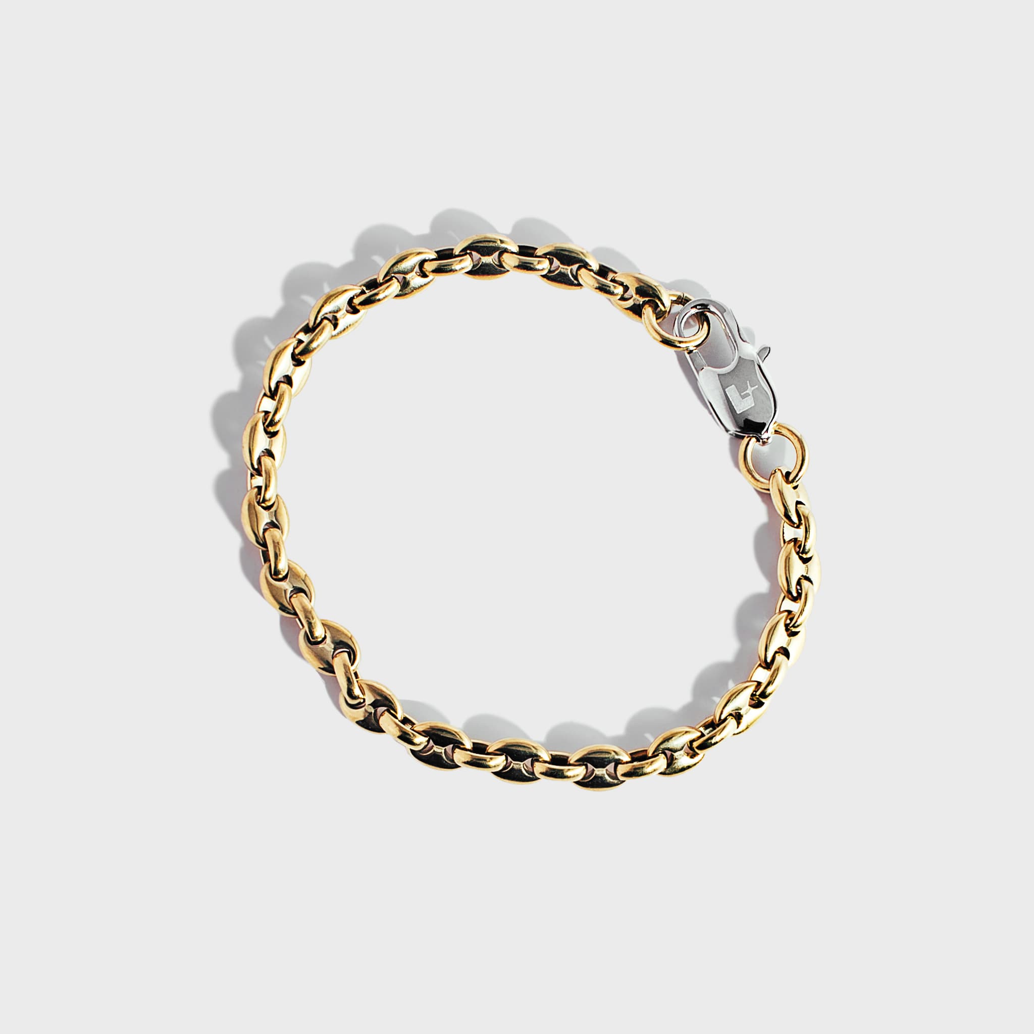 Gold mariner chain bracelet with silver oval clasp on white background
