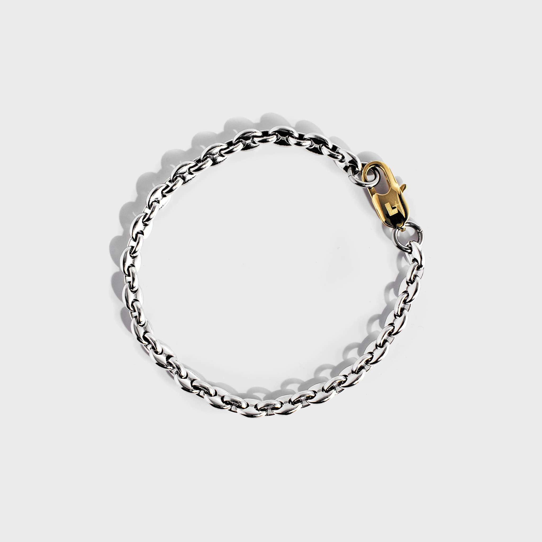 Silver mariner chain bracelet with gold oval clasp on white background