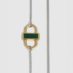 A close-up of a gold padlock-shaped pendant necklace with a dark green rectangular inlay, suspended on a silver-toned chain against a light gray background.