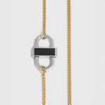 A close-up of a gold chain necklace featuring a silver-toned padlock-shaped pendant with a black rectangular inlay, shown against a light gray background.