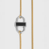 A close-up of a gold chain necklace featuring a silver-toned padlock-shaped pendant with a black rectangular inlay, shown against a light gray background.