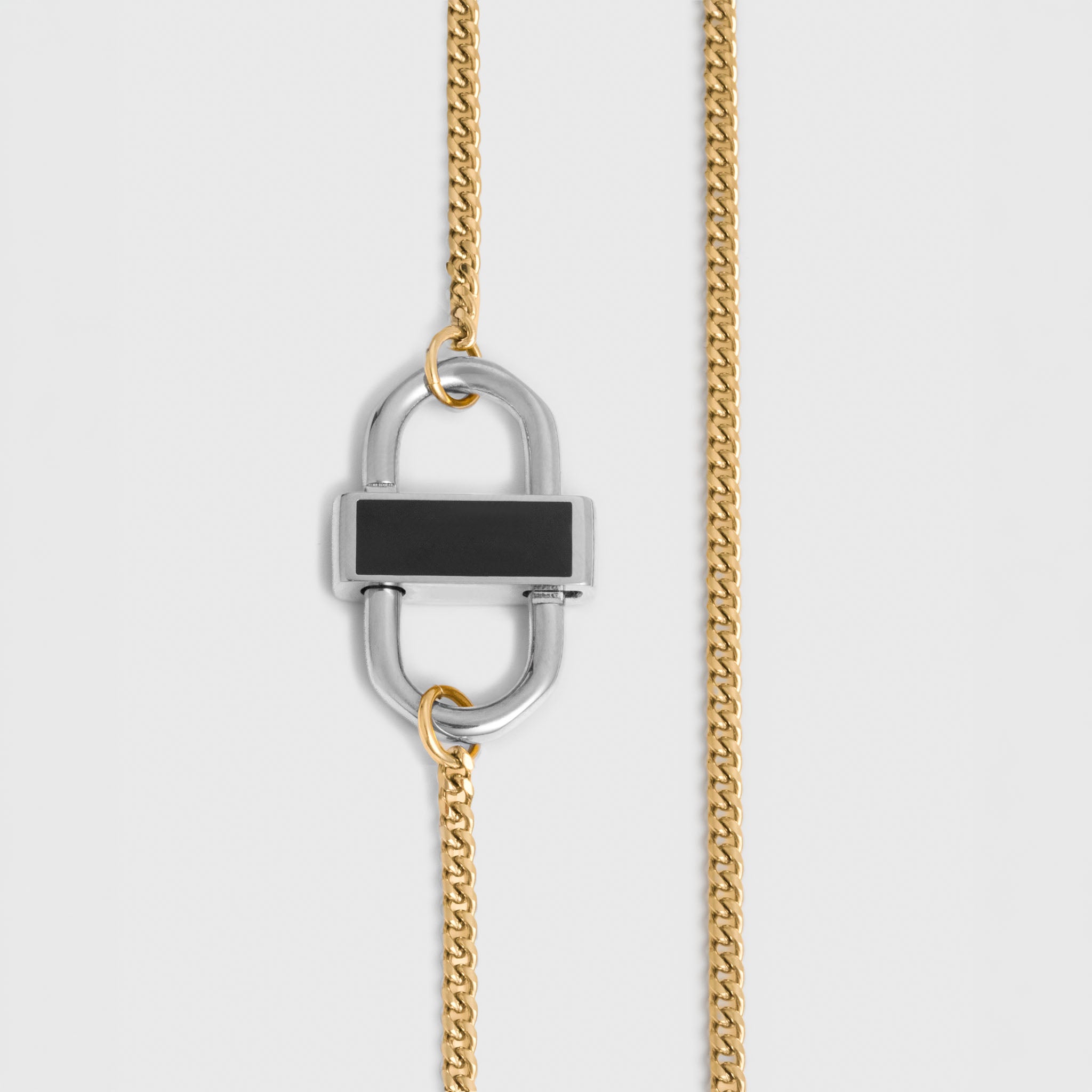 A close-up of a gold chain necklace featuring a silver-toned padlock-shaped pendant with a black rectangular inlay, shown against a light gray background.