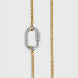 A close-up of a gold-toned chain necklace with a silver-toned carabiner clasp, shown against a light gray background.
