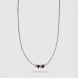 A silver ball chain necklace with a central pendant featuring five small hexagonal beads in silver, black, and rose gold, displayed against a light gray background.