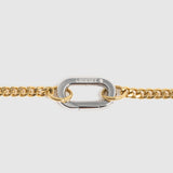 A close-up of a gold chain bracelet featuring a central silver-toned carabiner clasp engraved with the brand name Lockset