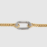 A close-up of a gold chain featuring a central silver-toned carabiner clasp engraved with the brand name 'Lockset". 

