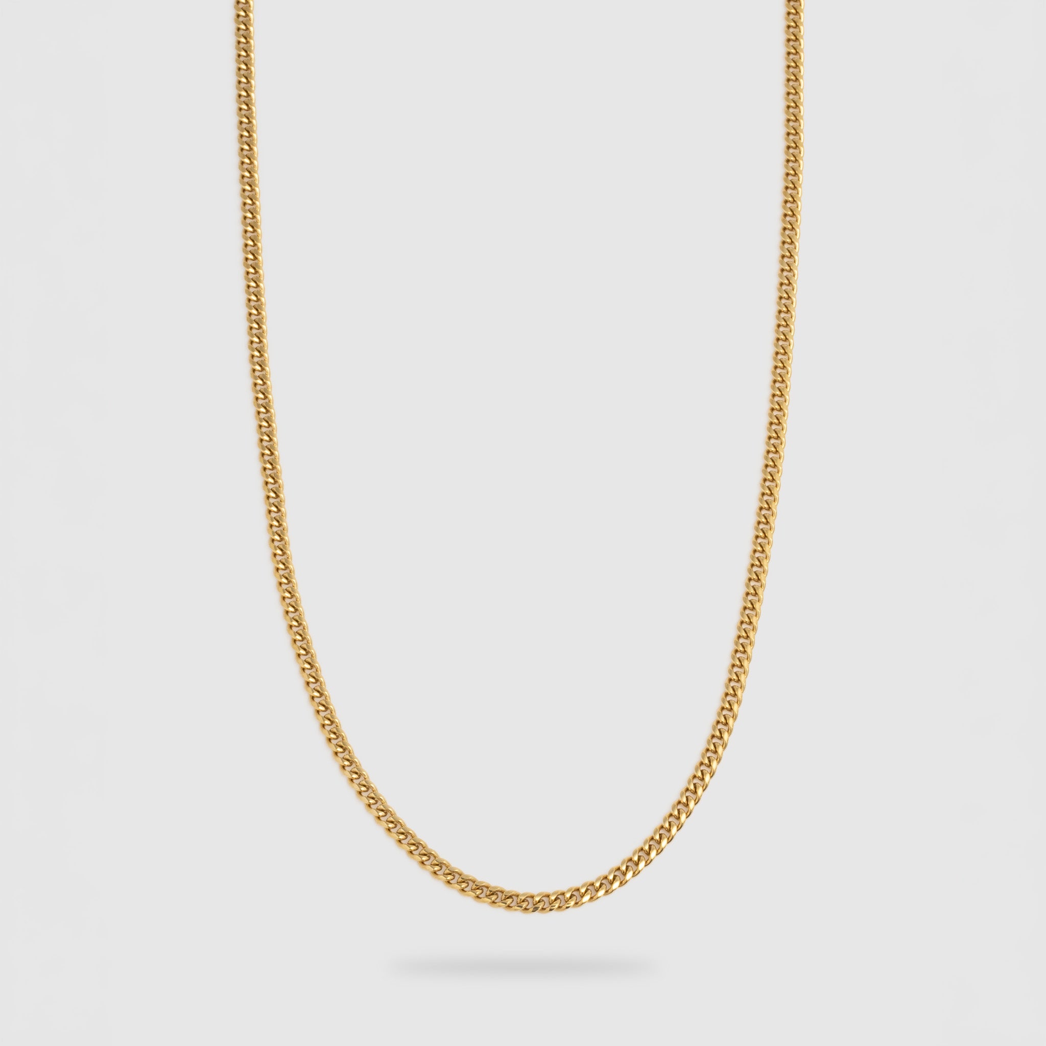 A gold chain necklace with a classic curb link design, shown hanging against a light gray background.