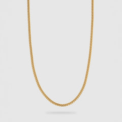 A gold chain necklace with a classic curb link design, shown hanging against a light gray background.