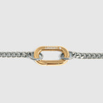 A close-up of a gold carabiner clasp connected to a silver-tone curb chain, shown against a light gray background.