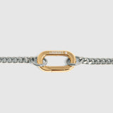 A close-up of a gold carabiner clasp connected to a silver-tone curb chain, shown against a light gray background.