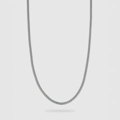 A silver-toned metal chain necklace with a classic curb link design, shown against a light gray background.