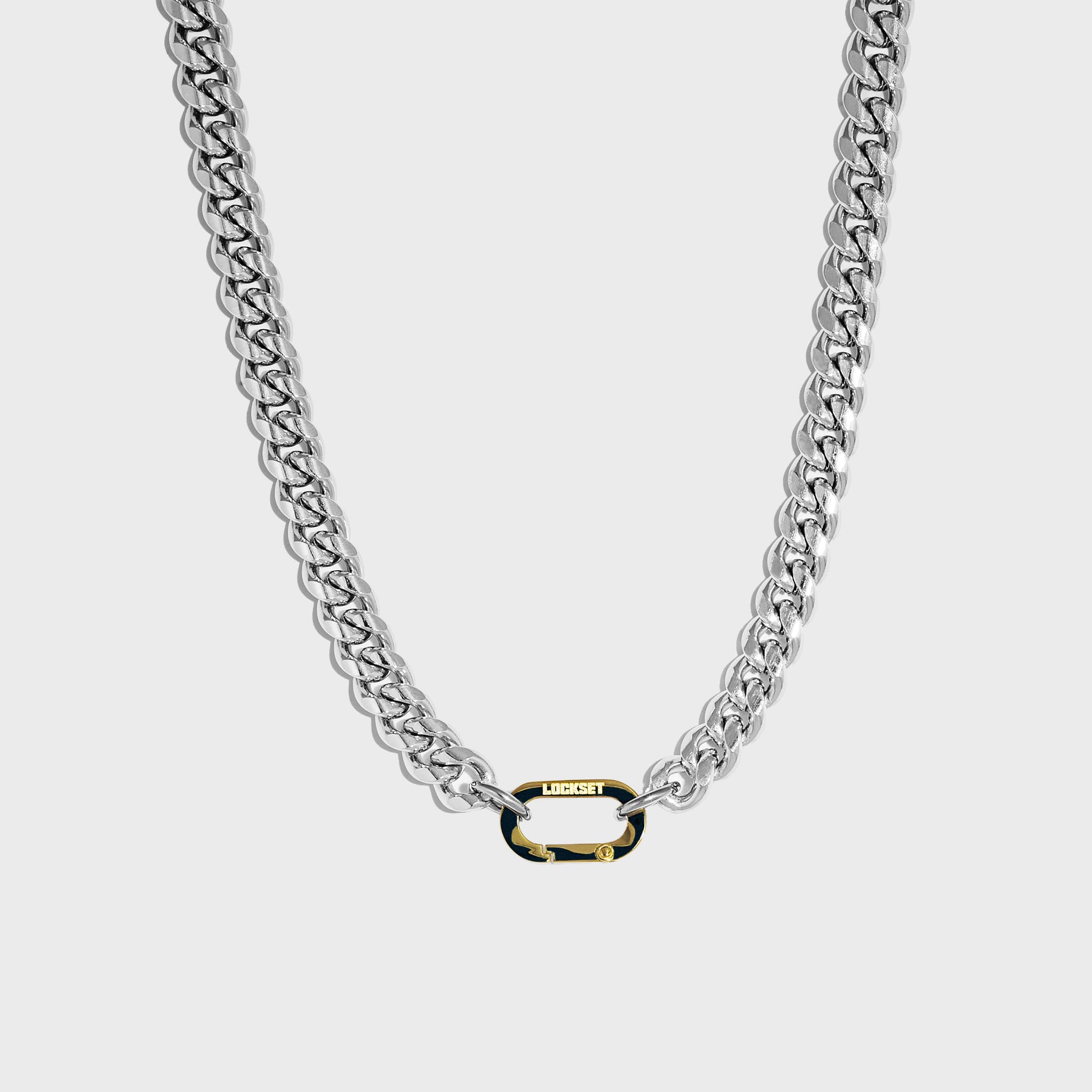 Thick silver cuban chain on white background with gold carabiner clasp 