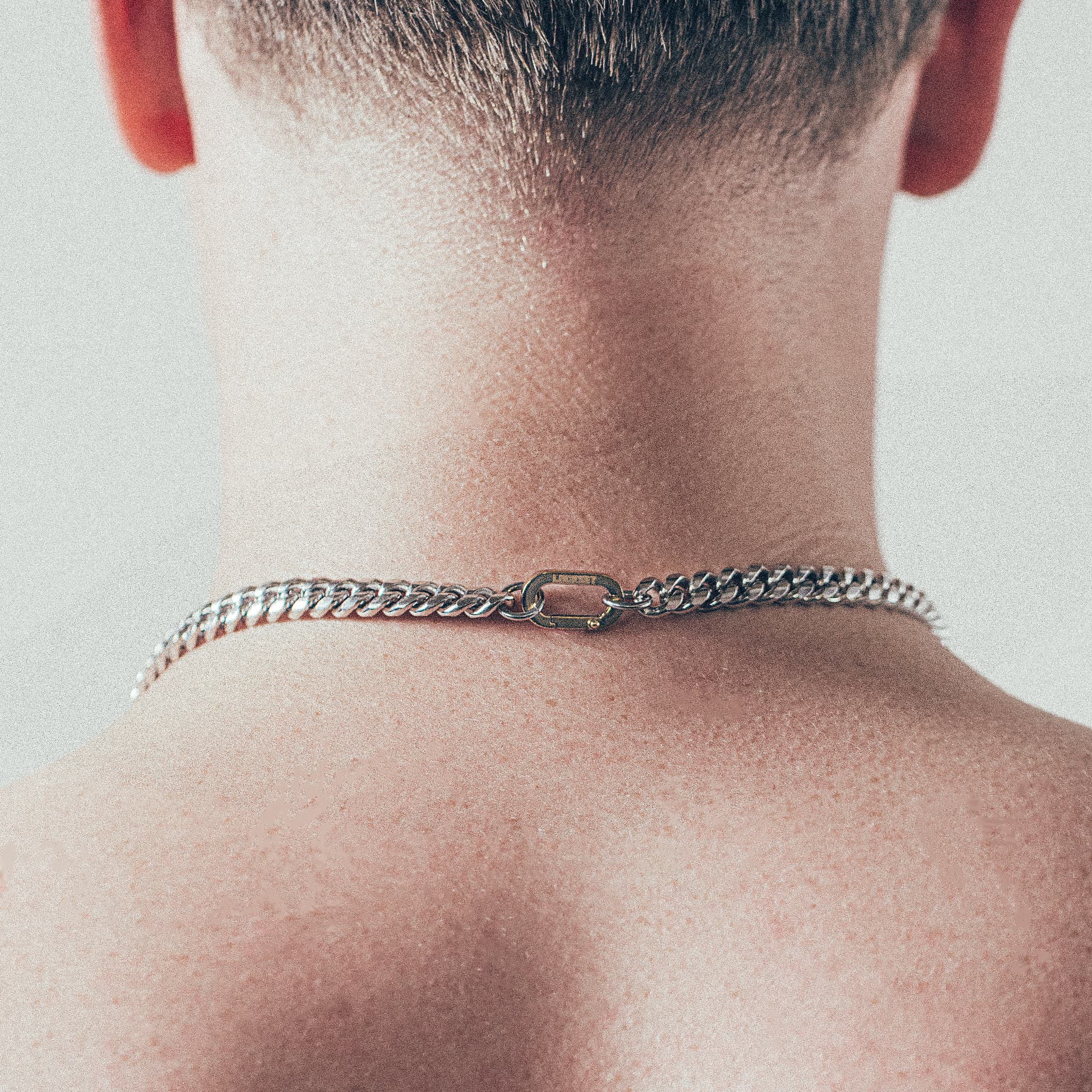 Close-up of man wearing thick silver Cuban chain necklace