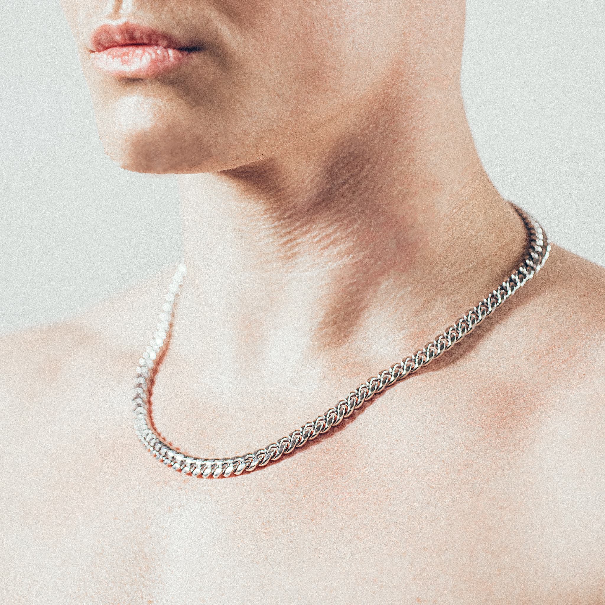 Close-up of man wearing thick silver Cuban chain necklace