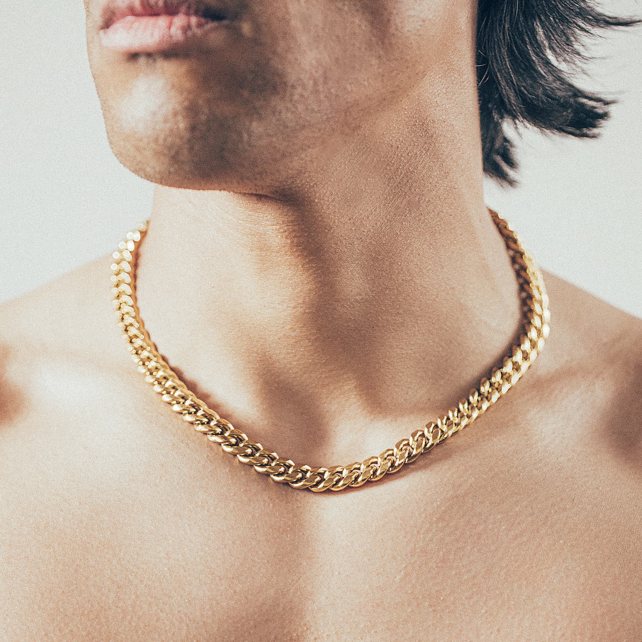 Close-up of man wearing thick gold Cuban chain necklace