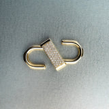 Gold double open-lock pendant featuring centered diamond detail on gray background