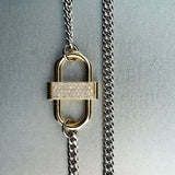 Silver chain necklace with gold double-lock pendant featuring centered diamond detail on gray background