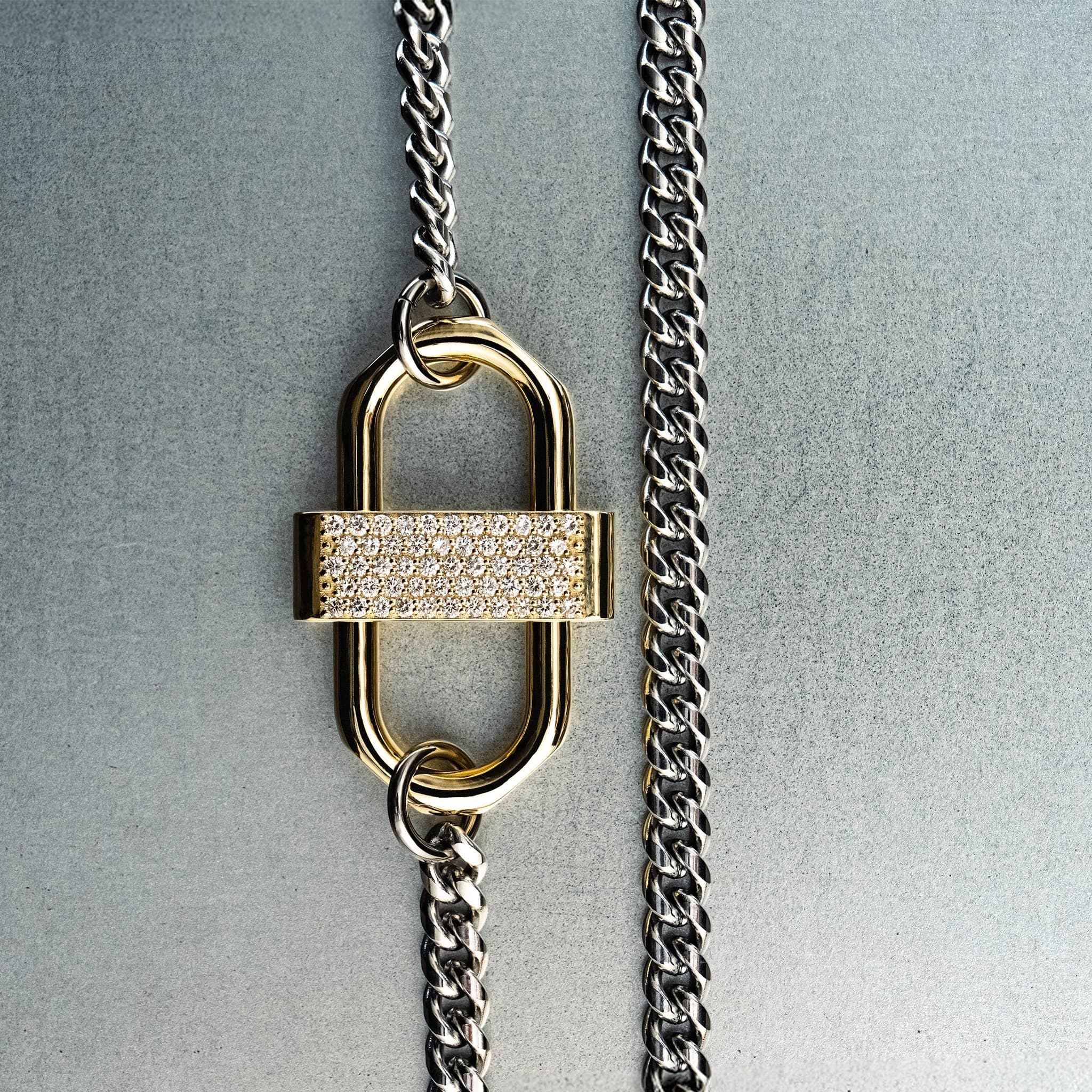 Silver chain necklace with gold double-lock pendant featuring centered diamond detail on gray background
