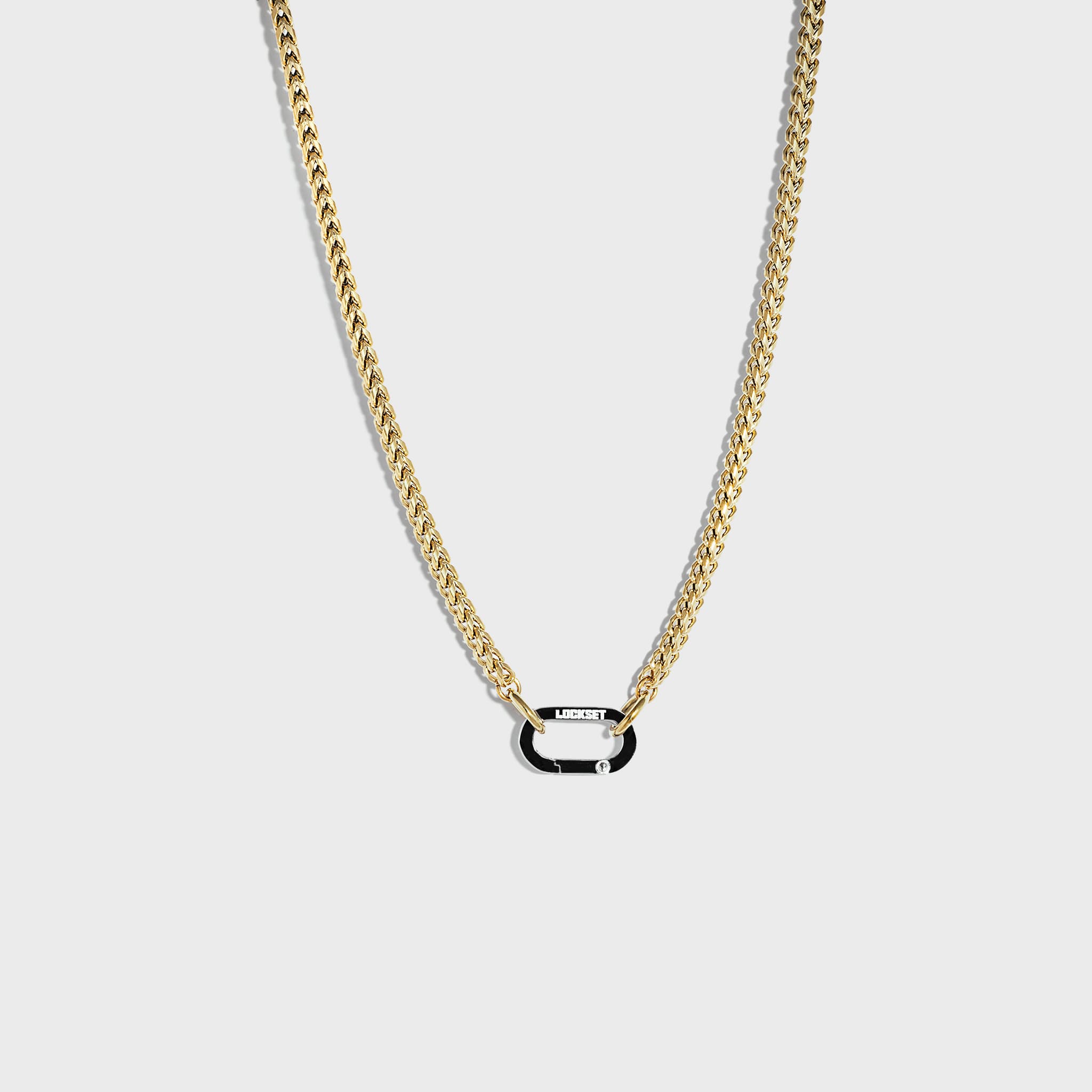 Gold chain with silver carabiner clasp on white background