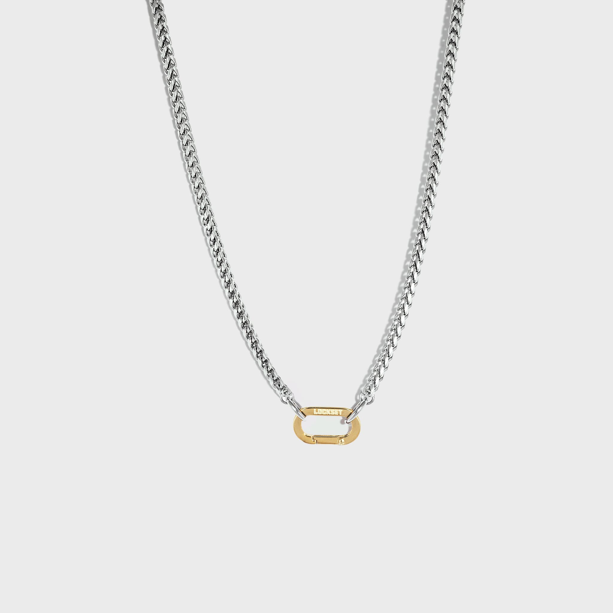 Silver chain with gold carabiner clasp on white background