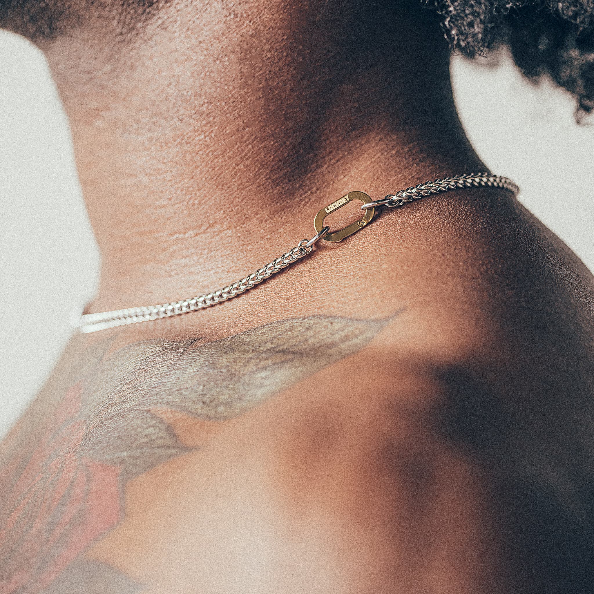 Close-up of man wearing silver chain necklace with gold carabiner clasp