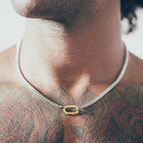 Close-up of man wearing silver chain necklace with gold carabiner clasp