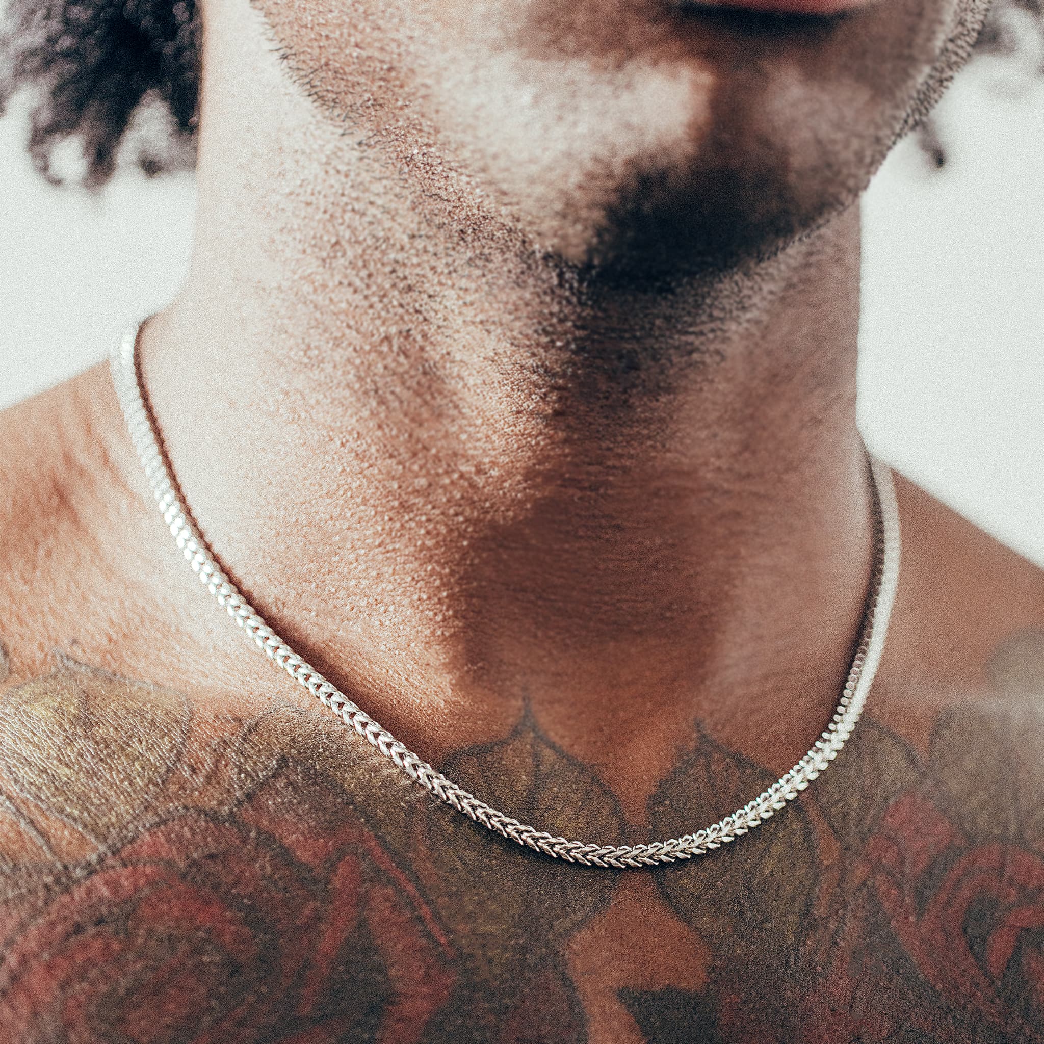 Close-up of man wearing silver chain necklace 